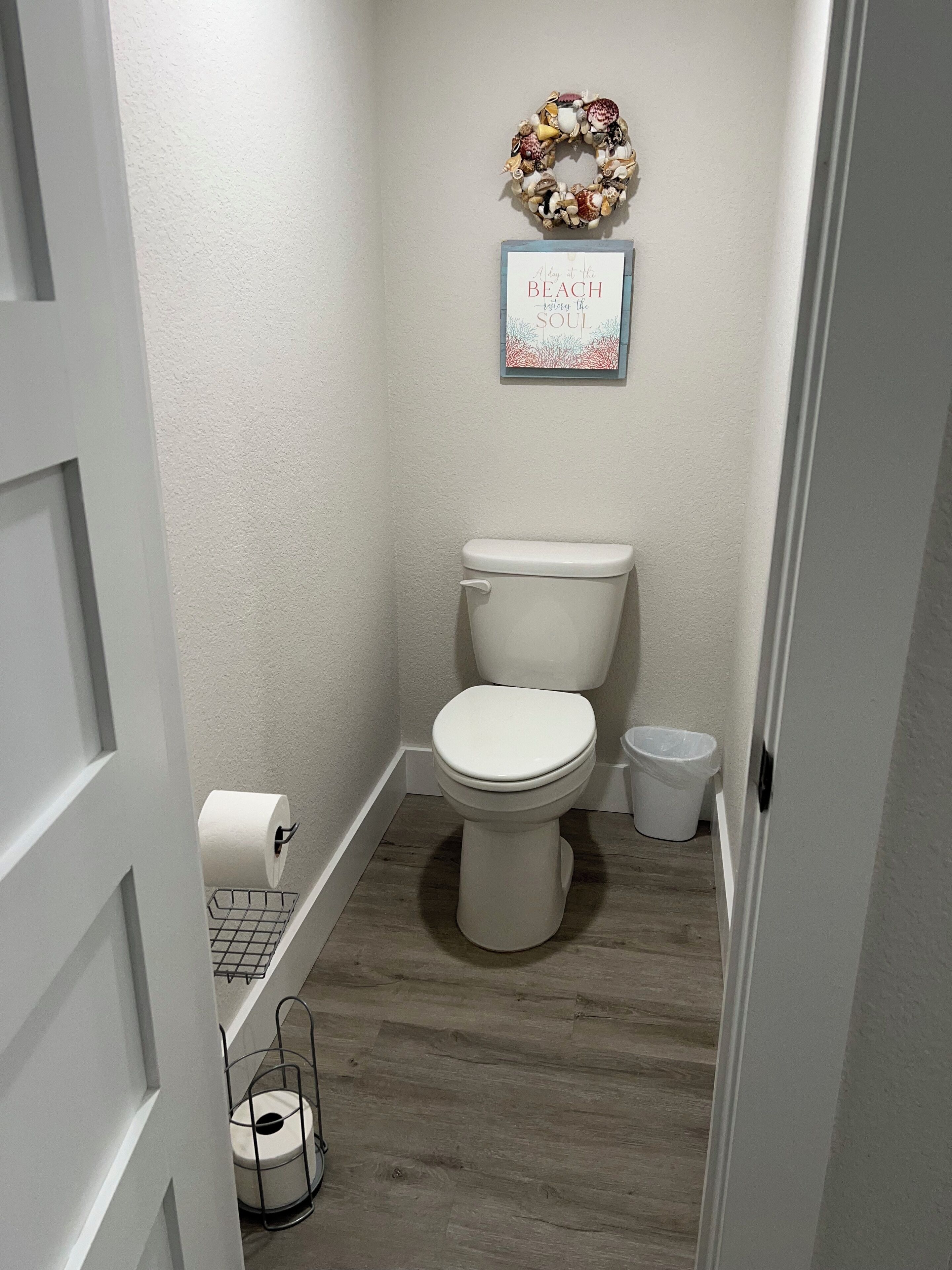 A small bathroom with a toilet, a trash can, and a toilet paper holder.