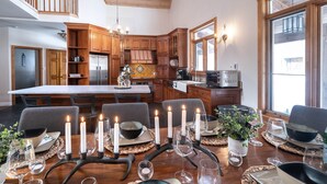 A spacious kitchen with wooden cabinets, a central island, and a dining area set for a meal. - Luxury Chalet in the Woods w/ Pool & Hot Tub, Near Wasaga Beach & Blue Mountain! (Minesing)