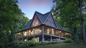 A large, two-story house with a prominent gable roof, a covered porch, and a stone foundation. - Luxury Chalet in the Woods w/ Pool & Hot Tub, Near Wasaga Beach & Blue Mountain! (Minesing)