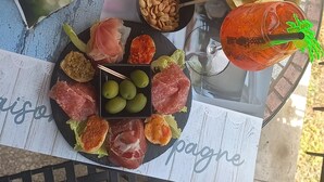 Taula amb diferents aliments i begudes, com ara patates cruixents, olives i una bebida amb una pajeta.