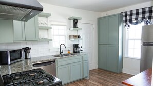 A kitchen with light blue cabinets, a stainless steel stove, a microwave, and a coffee maker.