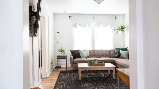 A living room with a sectional sofa, a coffee table, a floor lamp, and a potted plant.