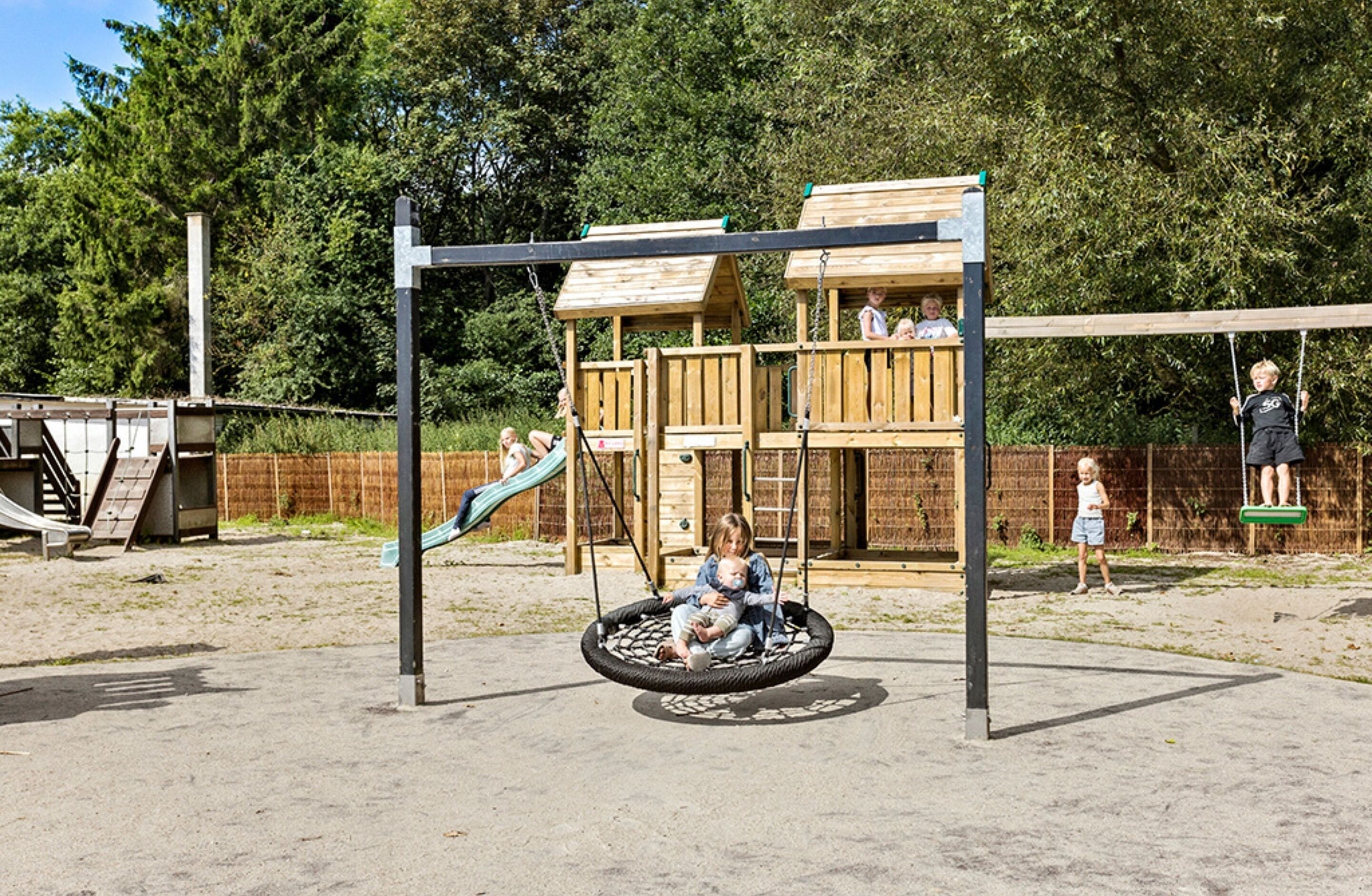 Un parque infantil con columpios, un tobogán y una estructura para escalar.