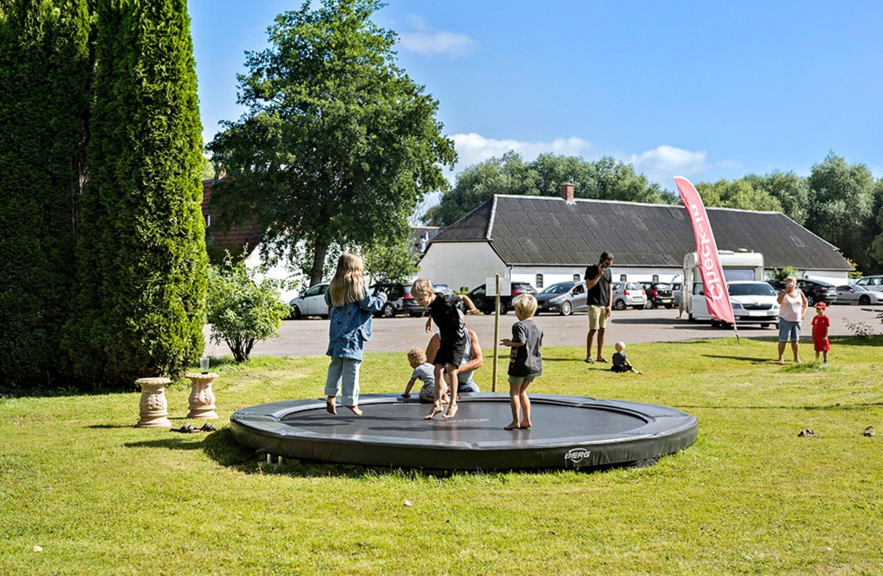 Un trampoline rond, installé dans un espace herbeux, avec des personnes autour.