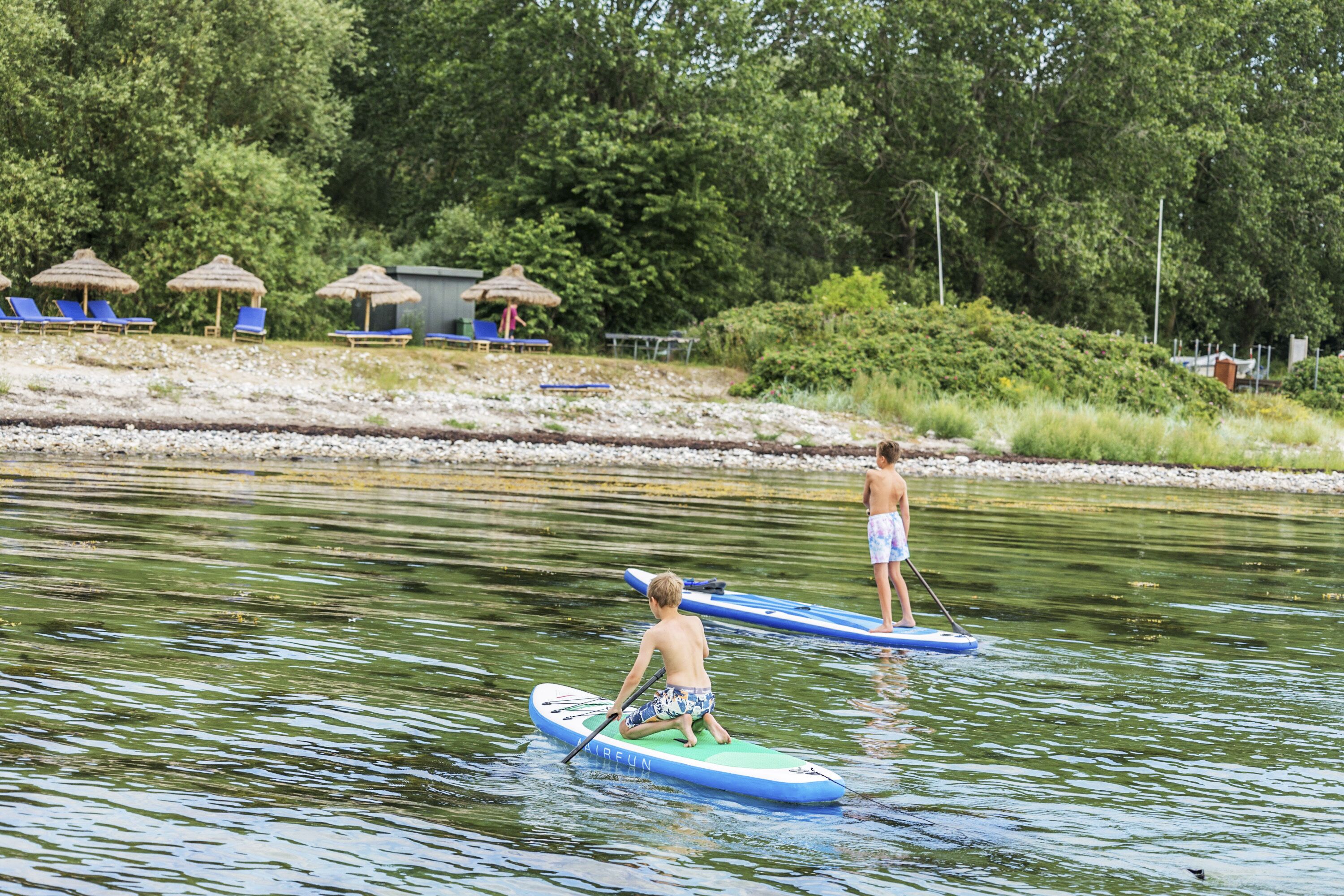 Un río con tablas de remo, un muelle y varios sombrillas de playa.