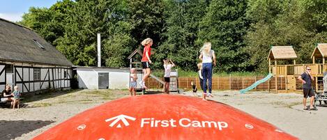 A sandy area with a red mat labeled "First Camp" and a playground with wooden play structures.