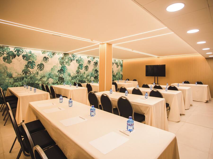 A conference room with multiple tables, chairs, and a large screen.