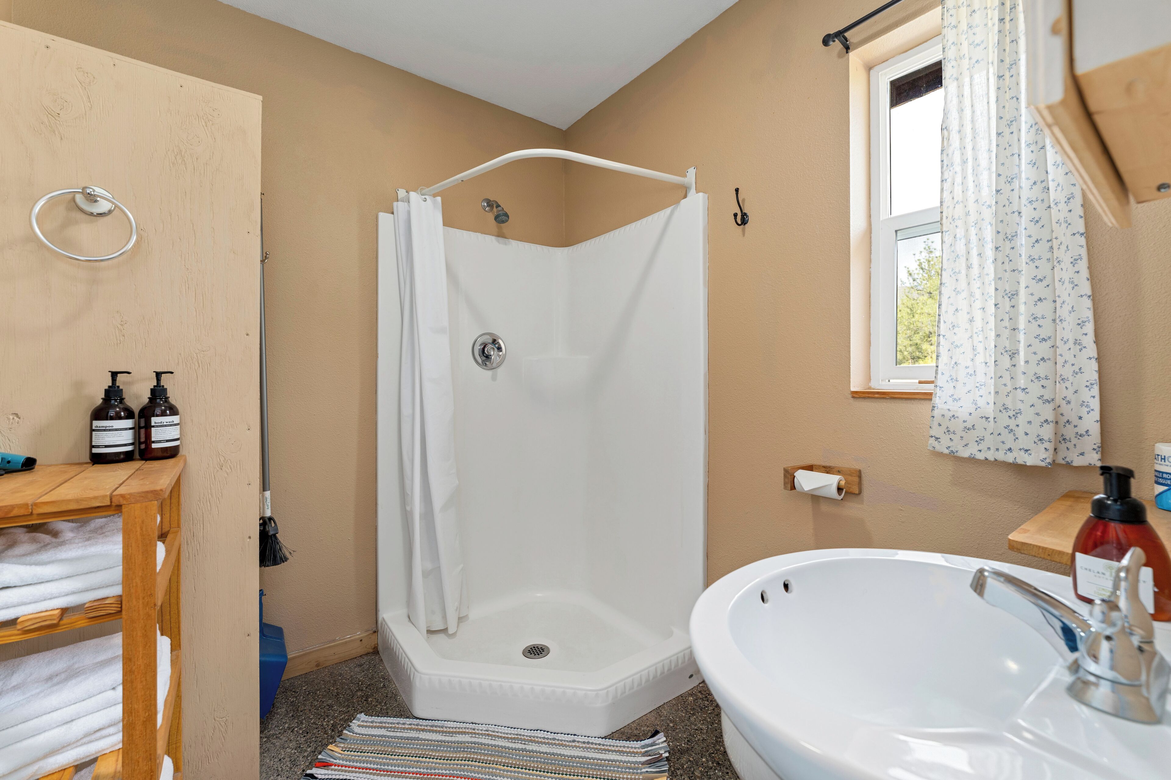 Un baño con ducha, lavamanos y estantes de madera con toallas.