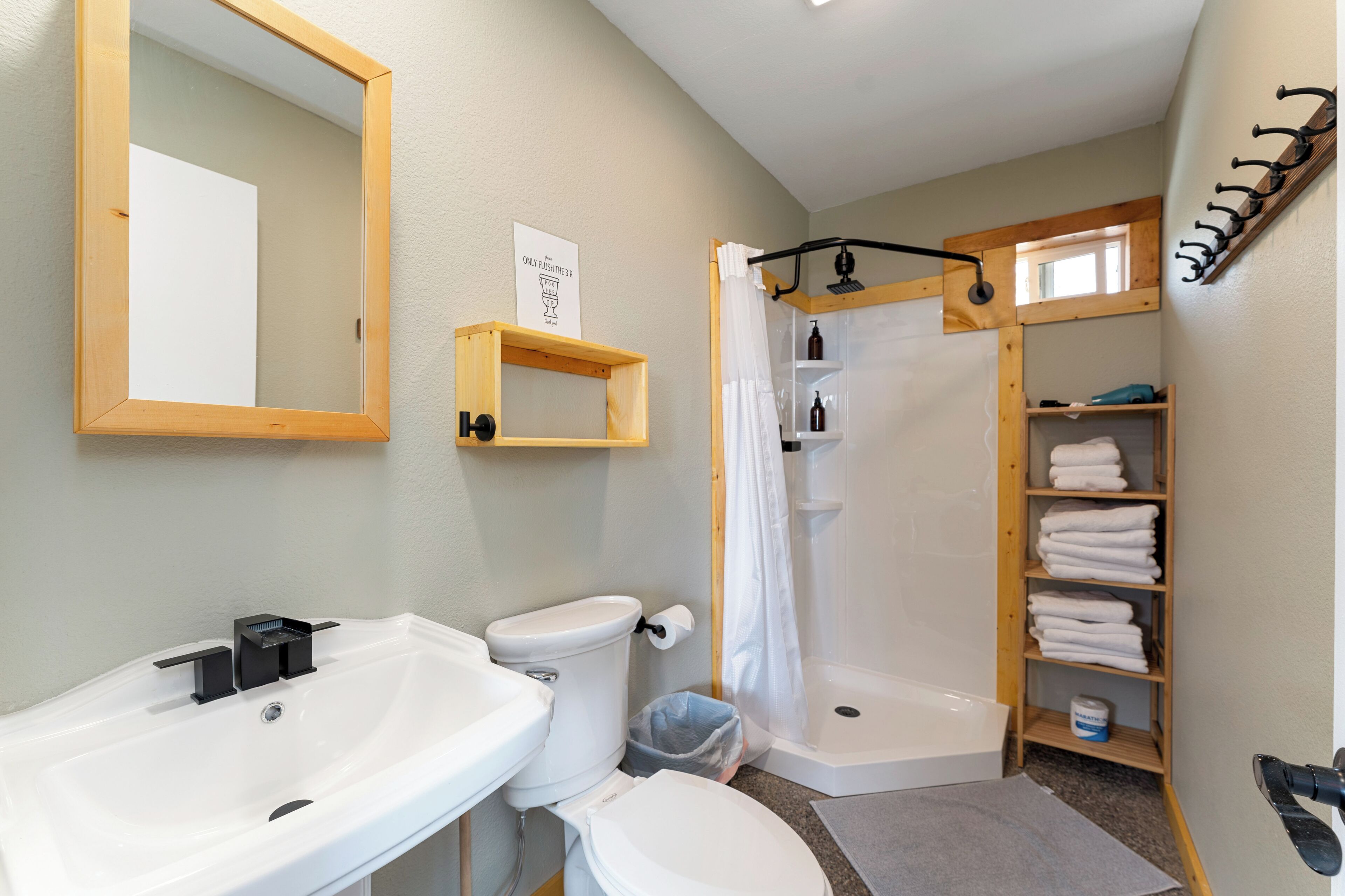 Een badkamer met een wastafel, toilet, douche en een handdoekhouder.