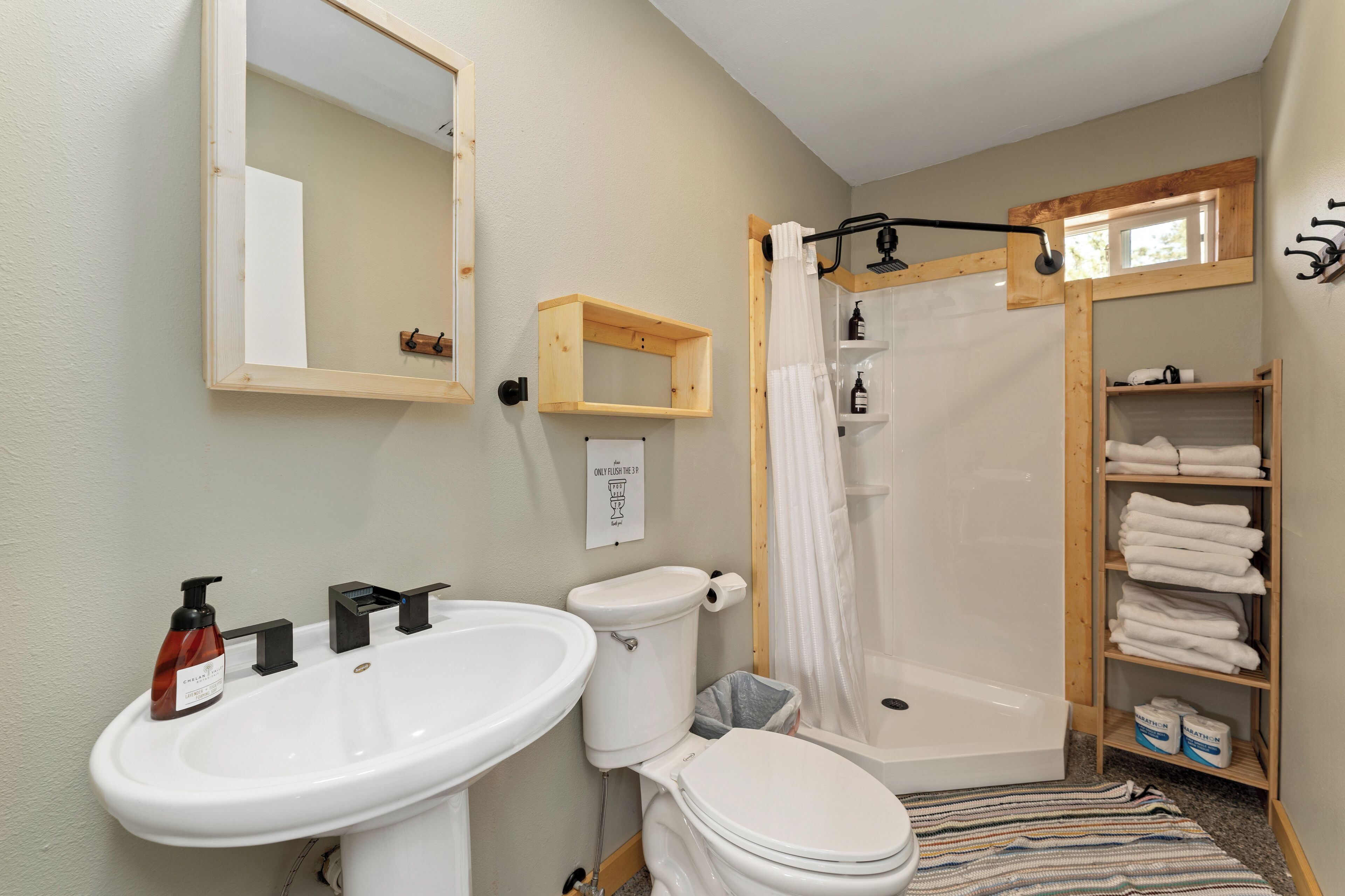 Une salle de bain équipée d’un lavabo, de toilettes, d’une douche et d’une étagère avec des serviettes.