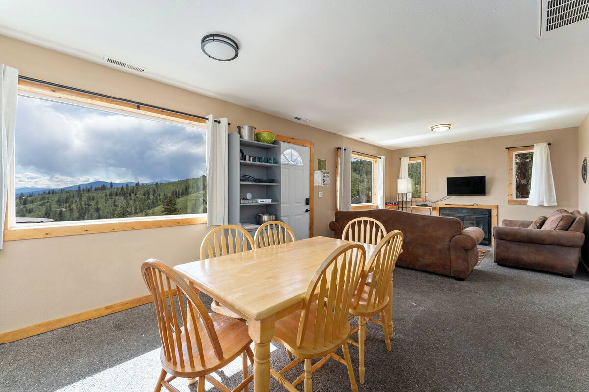 A spacious living area with a wooden dining table, chairs, a sofa, and a television.