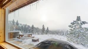 A snowy landscape with a wooden cabin and picnic tables visible through a window. - Echo Valley Resort & Cabins (Manson)