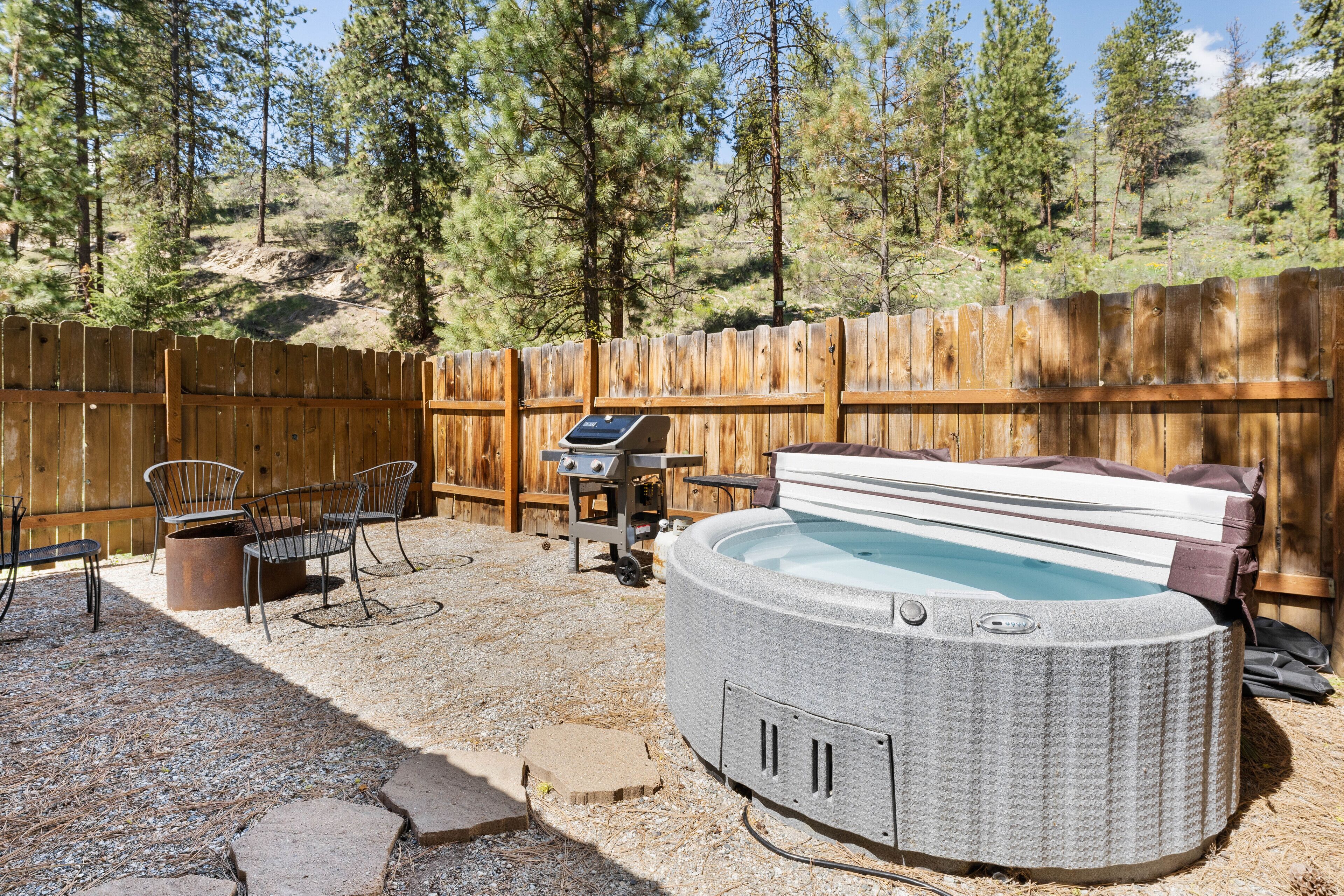 Un patio trasero con un jacuzzi, mobiliario de exterior y una parrilla.