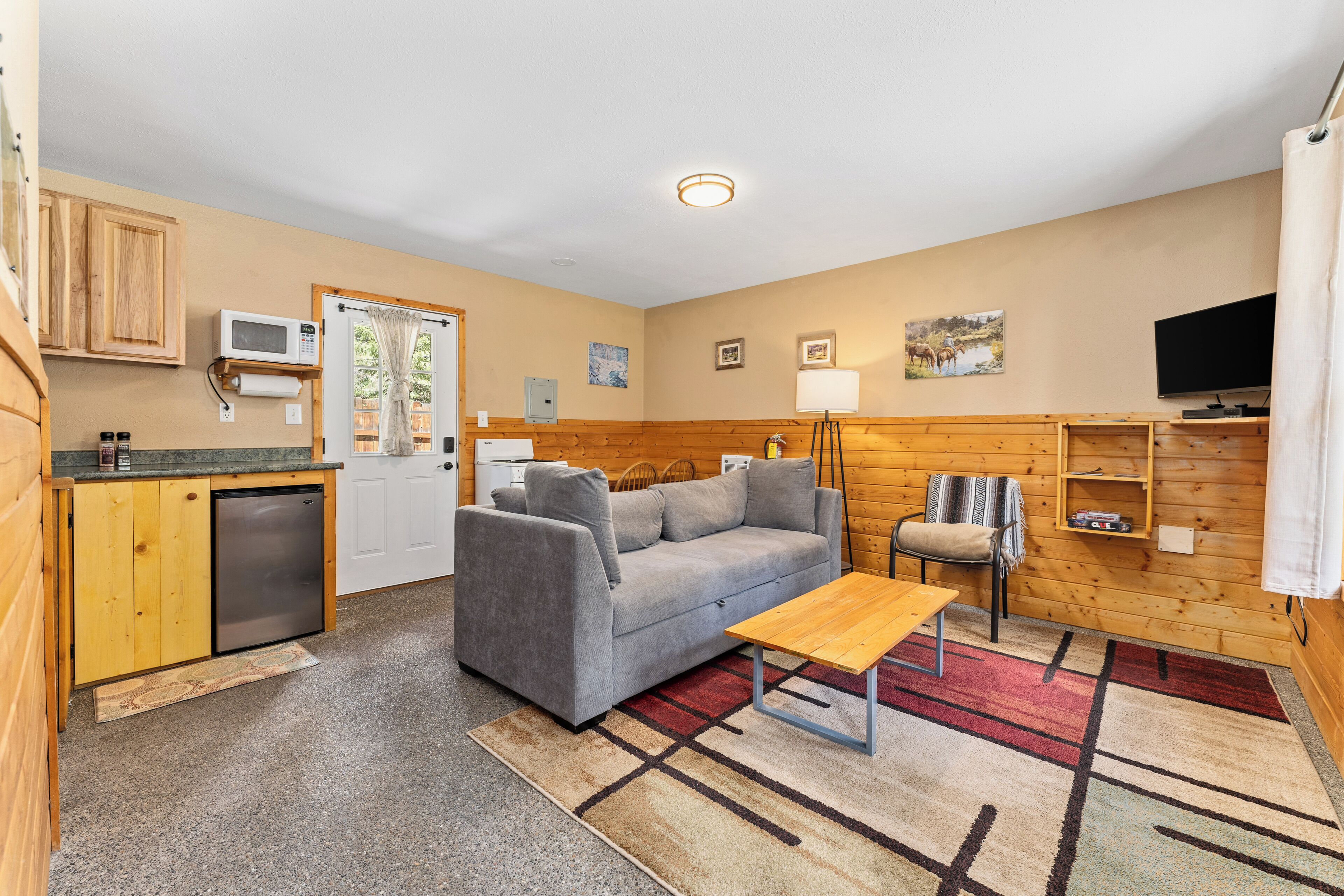 A compact living space with a kitchenette, a sofa, a coffee table, and a TV.
