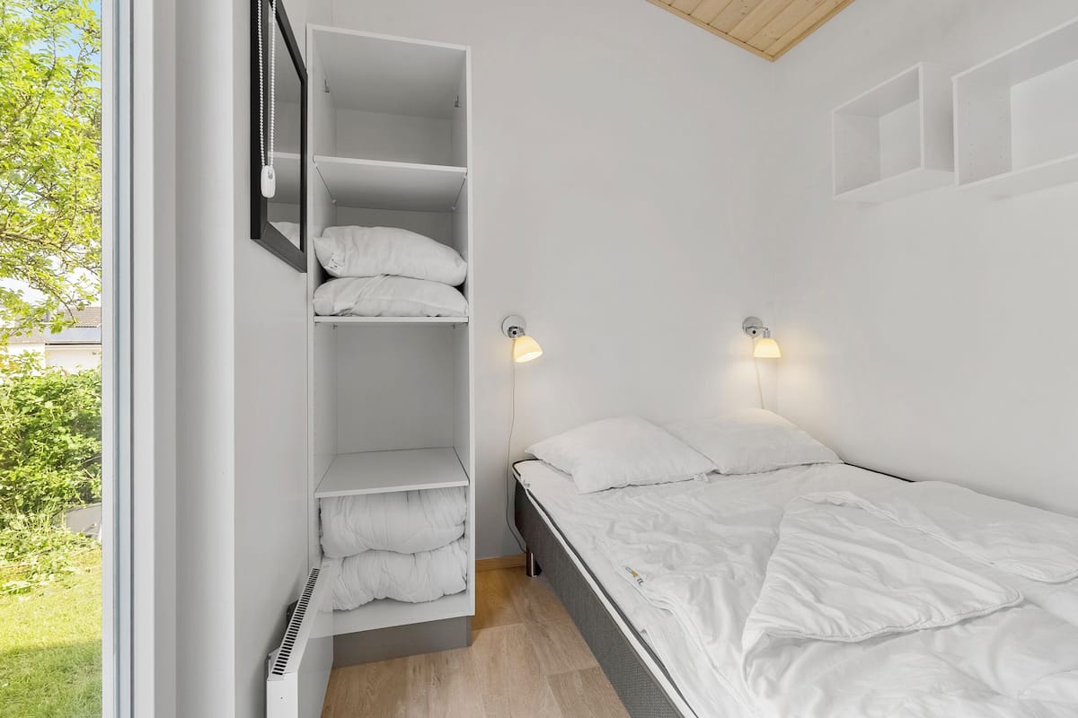 A bedroom with a bed, a built-in wardrobe, a mirror, and two wall-mounted lights.