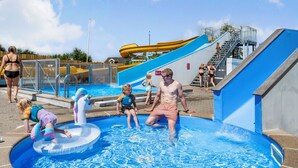 Zona de piscina con tobogán de agua y juguetes inflables.