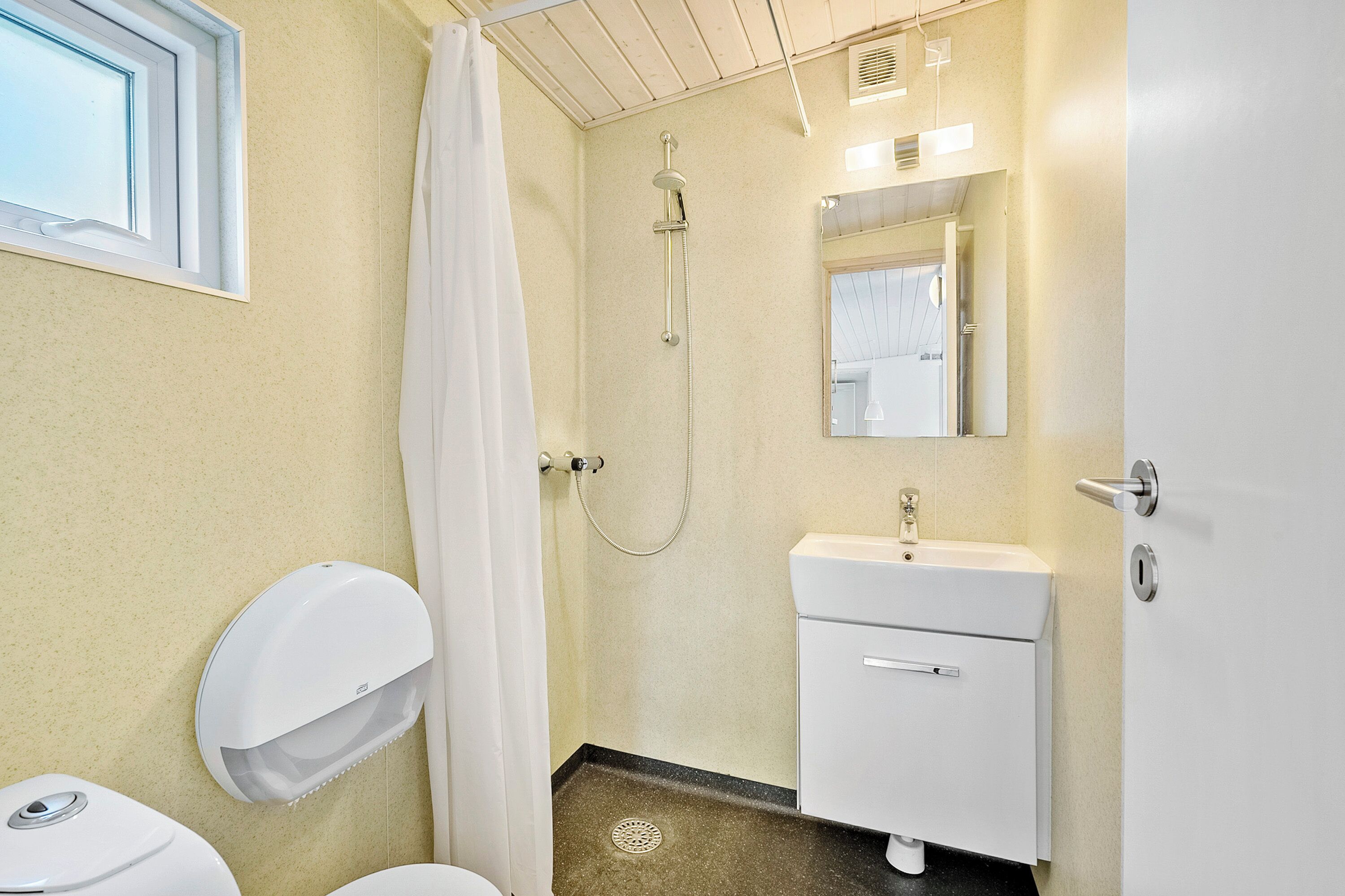A bathroom with a toilet, sink, shower, and a mirror.