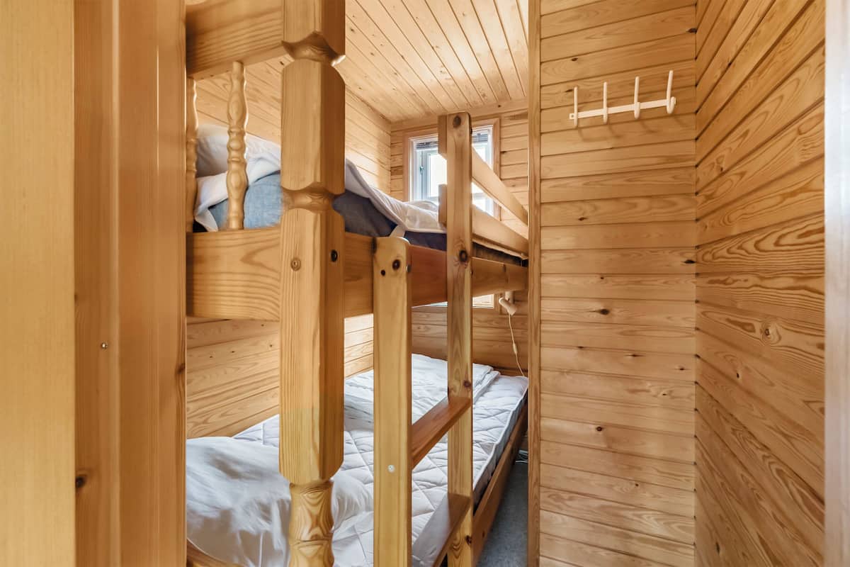 A wooden bunk bed room with a window and a coat rack.