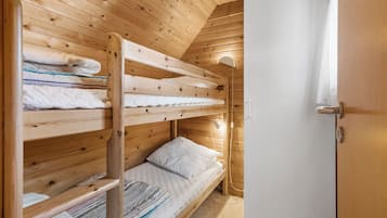 Habitació amb lliteres, parets de fusta i una porta blanca.