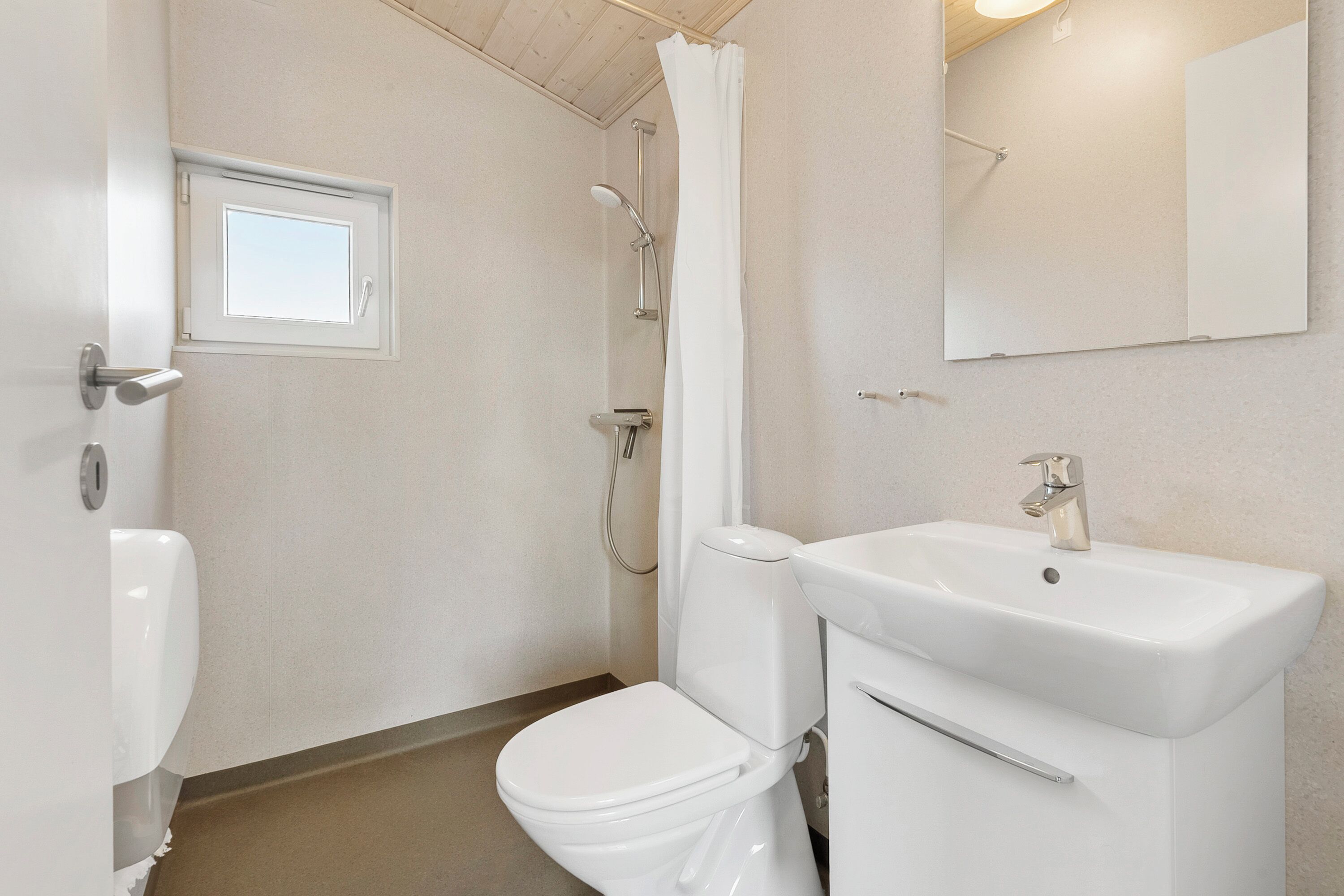 Une salle de bain avec des toilettes, un lavabo, une douche et une fenêtre.