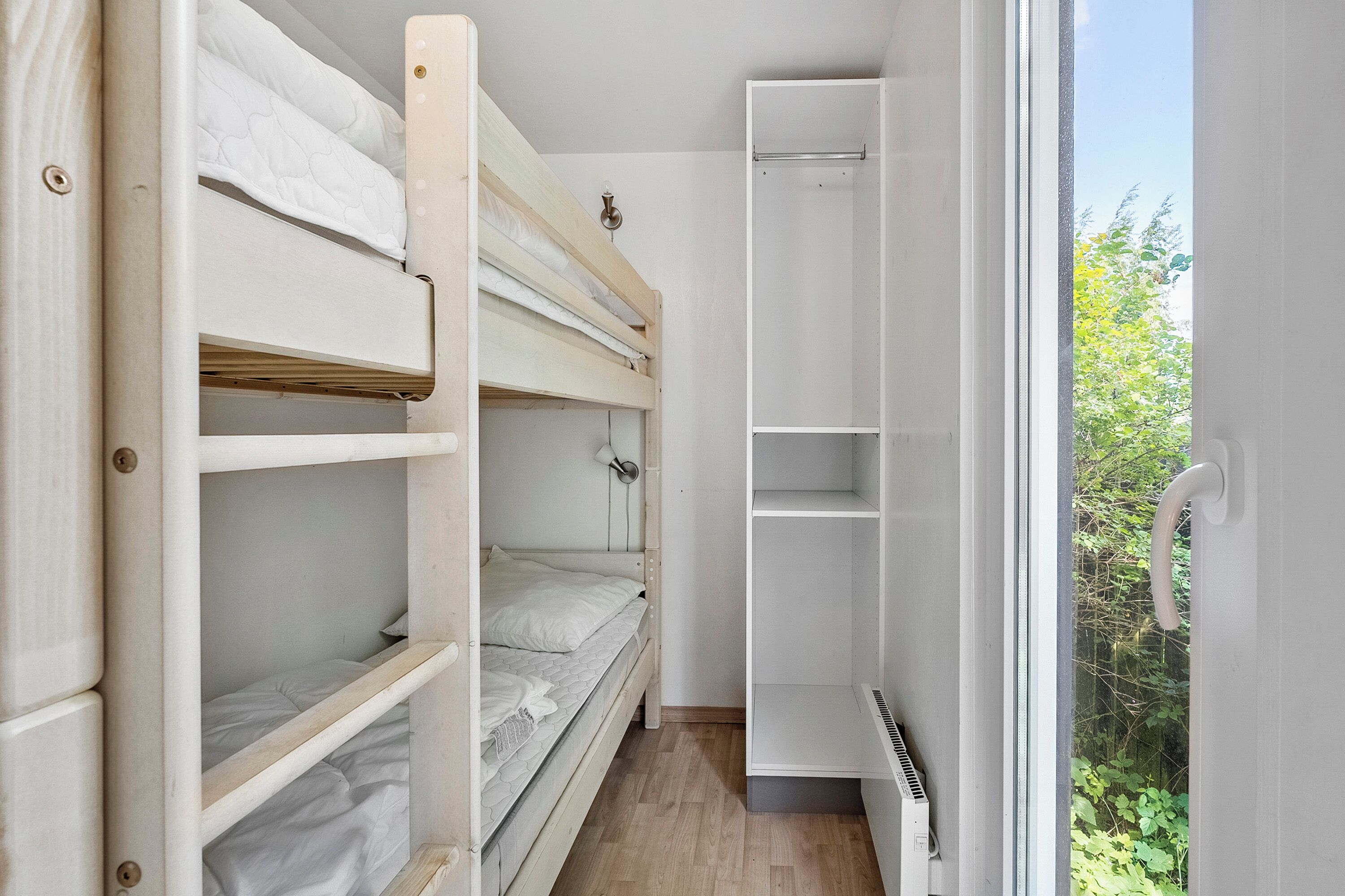 Une chambre avec un lit superposé, un placard intégré et un radiateur.