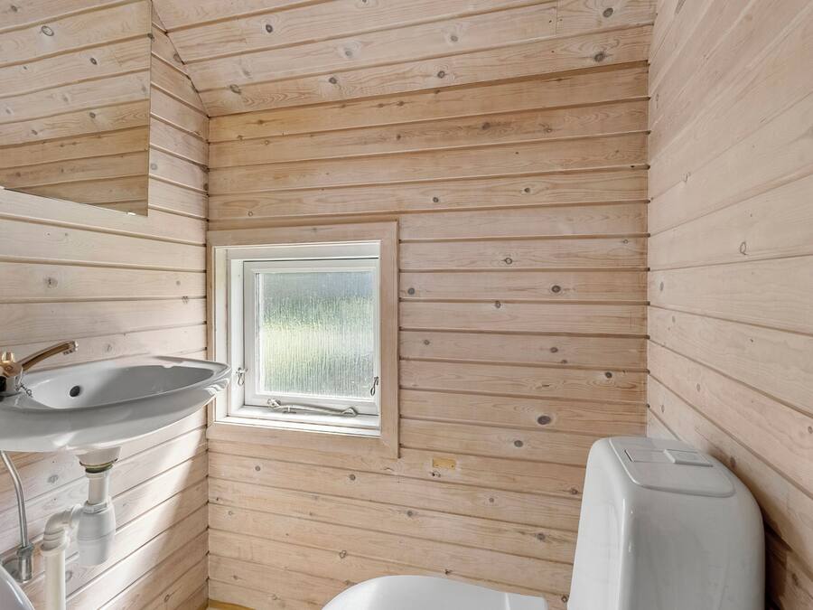 Bagno di una baita in legno con lavandino, finestra e WC.