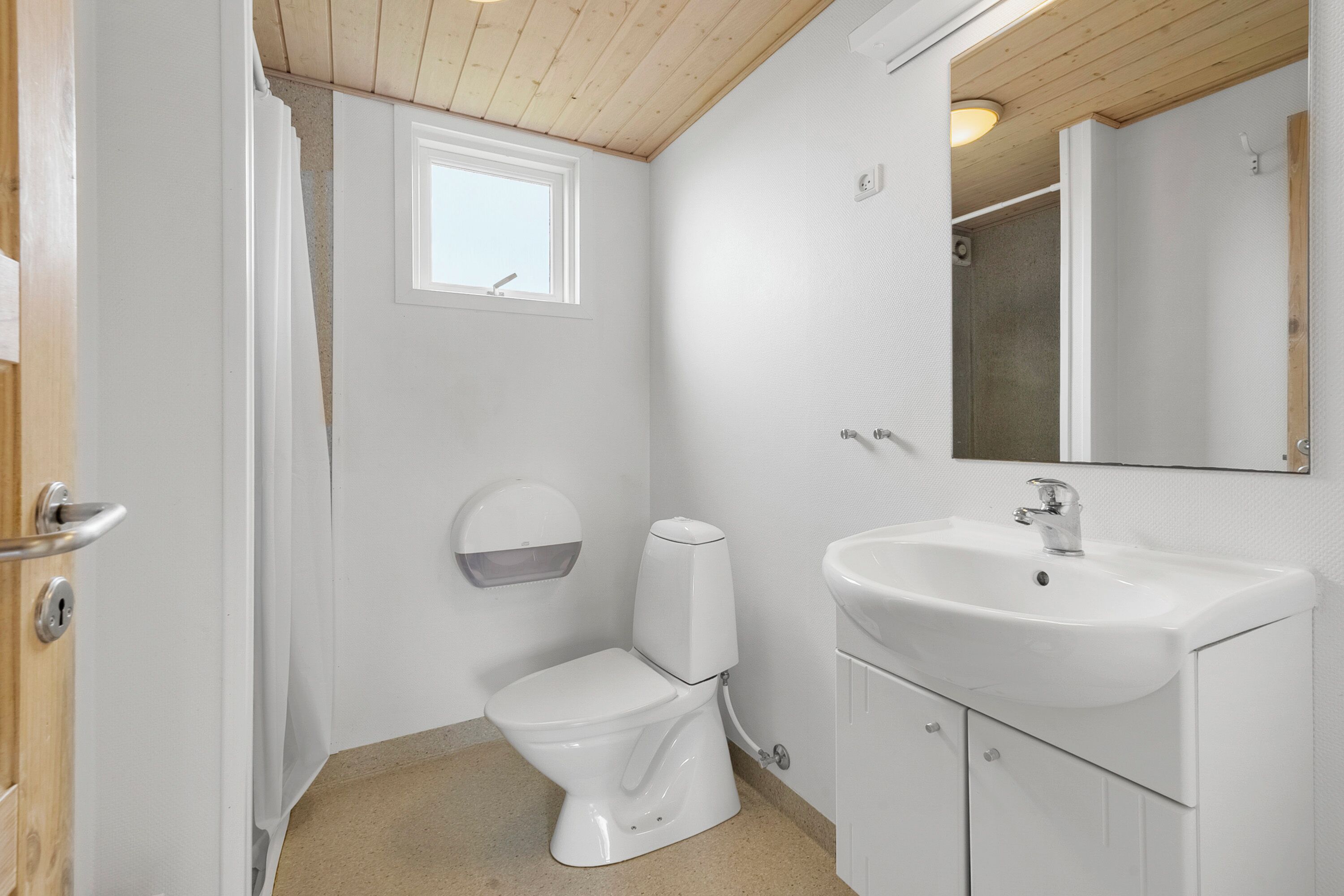 A small, white bathroom with a toilet, sink, and mirror.