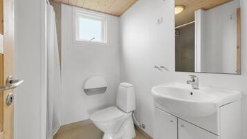 A small, white bathroom with a toilet, sink, and mirror.