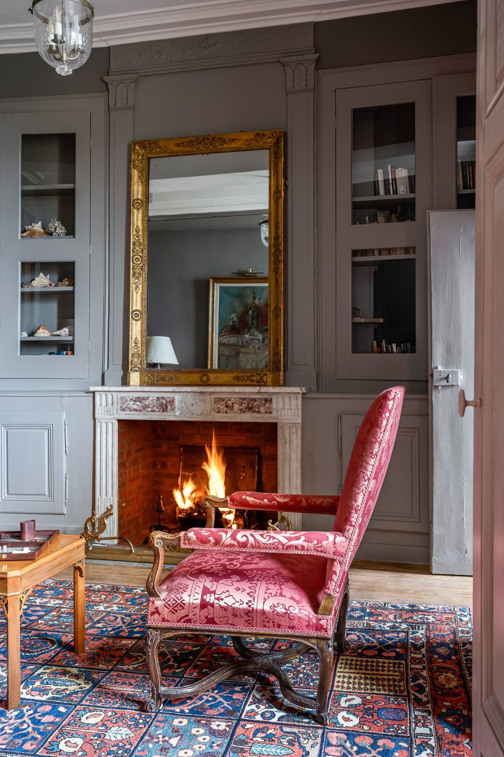 A room with a fireplace, a large mirror, and a patterned rug.