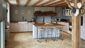 A kitchen with a wooden island, bar stools, white cabinets, and a stone countertop.