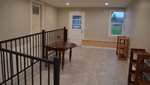 A spacious room with a wooden staircase, a dining table, and a window with a view of a green field.