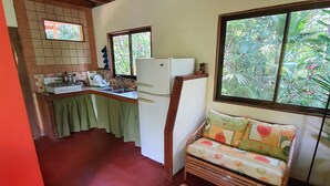 A compact room with a kitchen area, a sofa, and a small table.