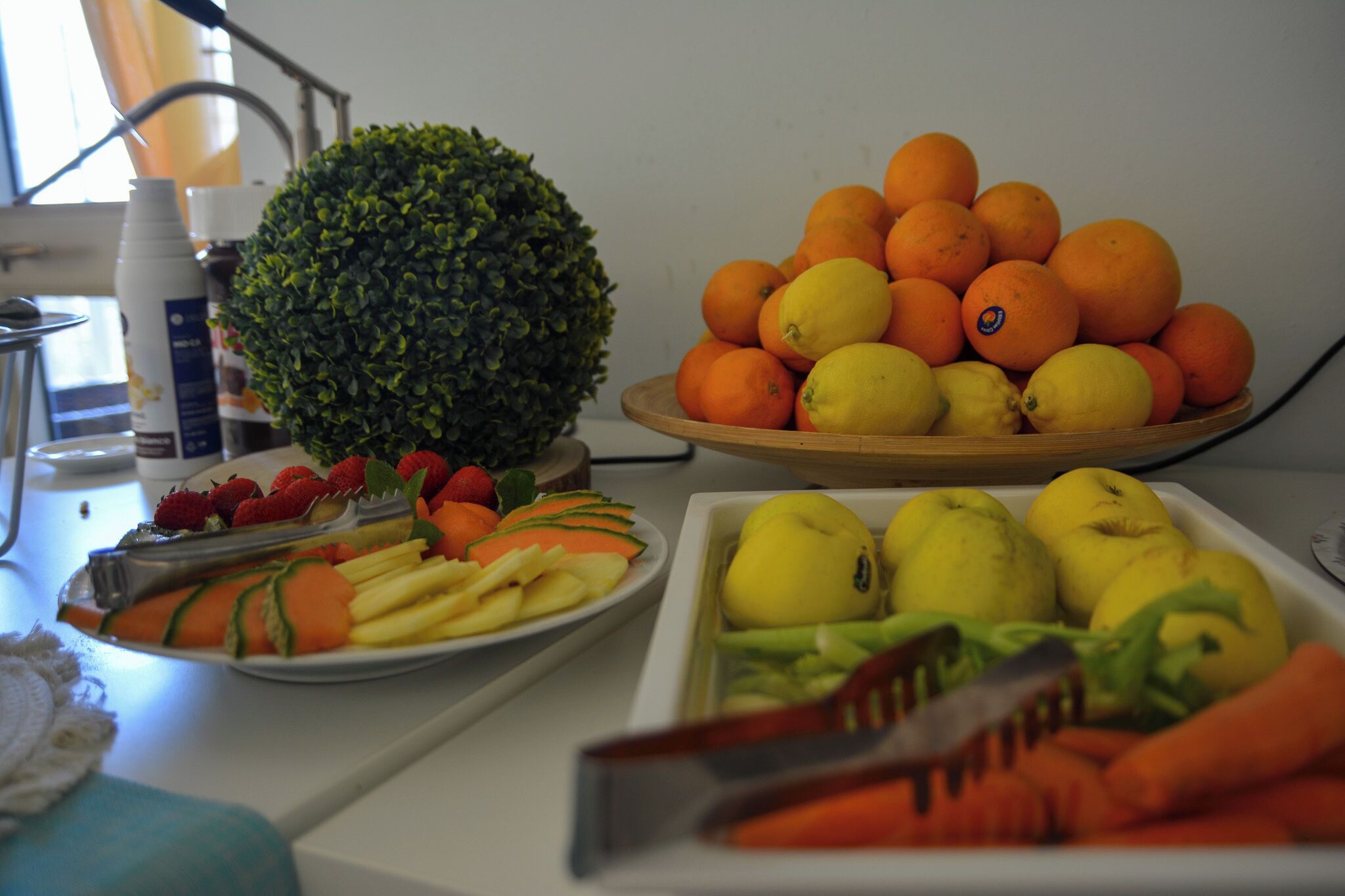 Un plan de travail de cuisine sur lequel on trouve divers fruits et légumes, notamment des oranges, des citrons, des fraises et des carottes.