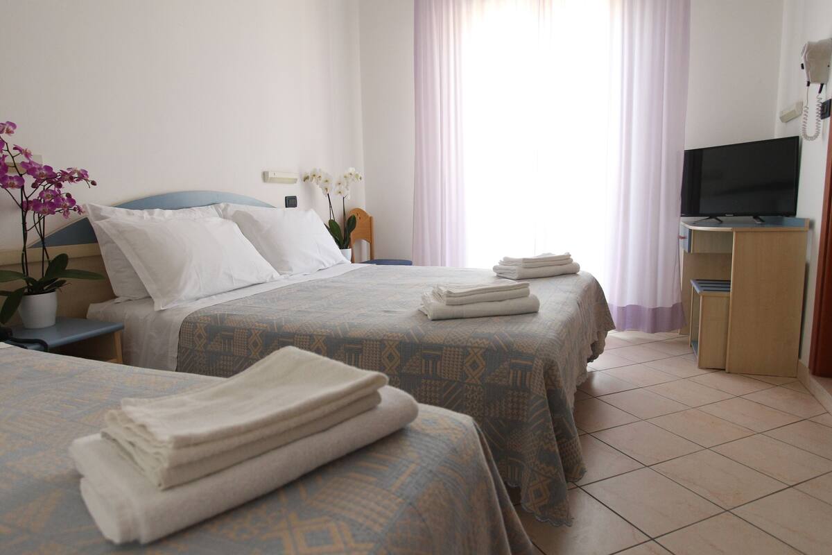 A hotel room with two beds, a TV, and a desk.