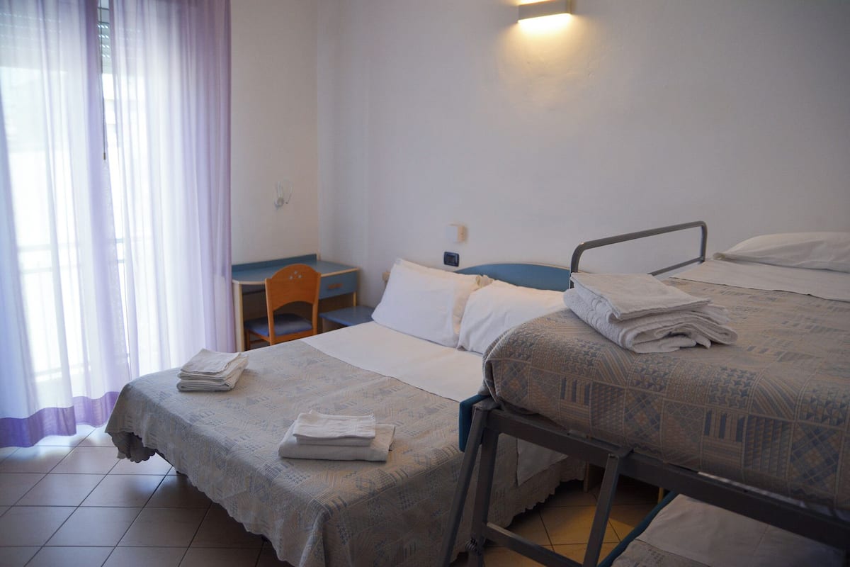 A hotel room with a bed, a desk, and a chair.