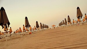 A beach with rows of umbrellas and lounge chairs. - Hotel Giorg - WaterPark Free Entrance (Rimini)