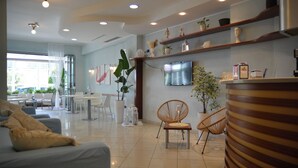 Un moderno vestíbulo de hotel con zona de estar, un televisor en la pared y un mostrador de recepción.