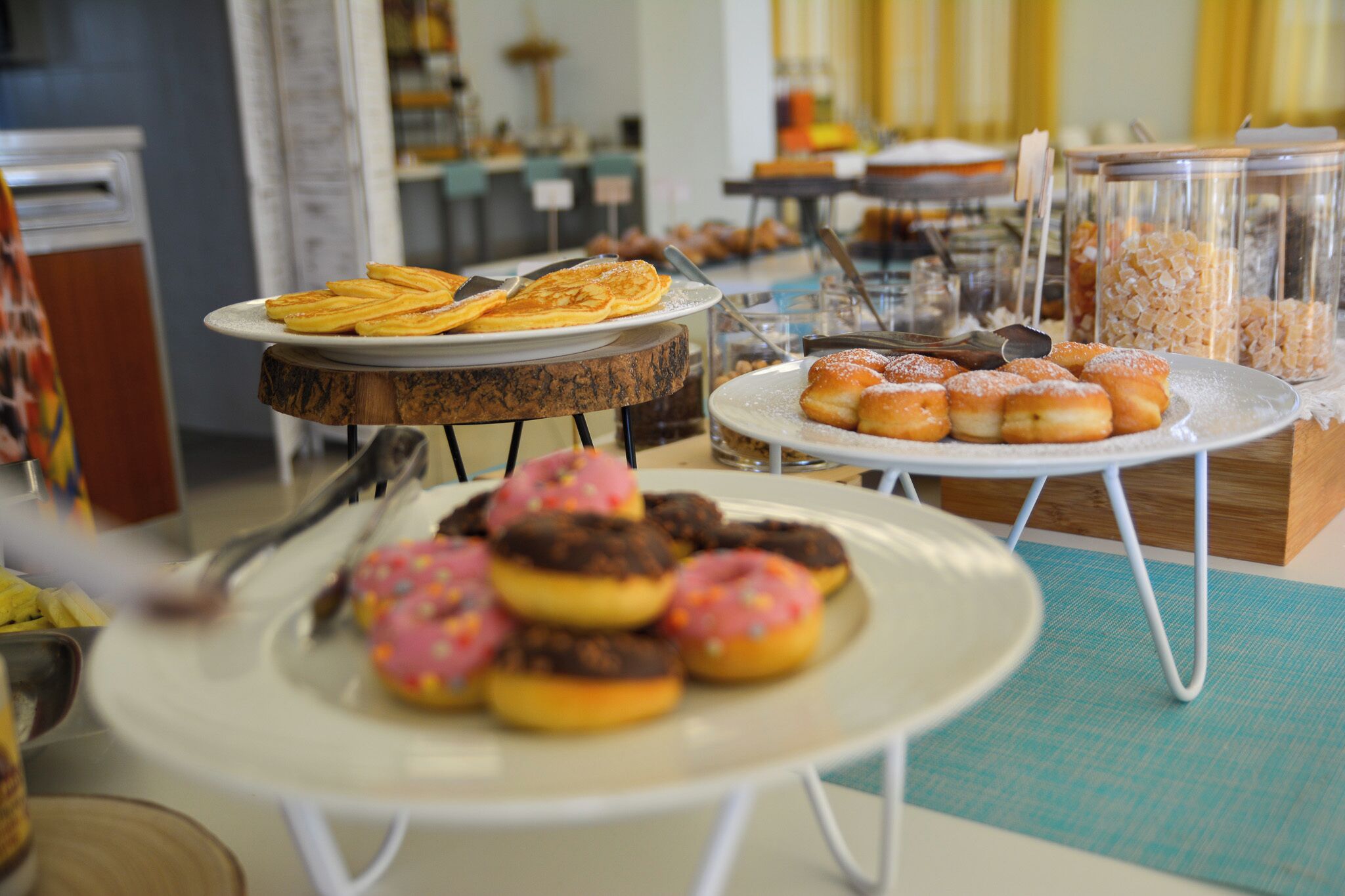 Un bufé con diversas opciones de pastelería y postres, incluyendo rosquillas y bollos en platos.