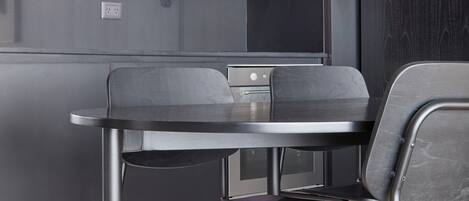 Een moderne keuken met donkere kastjes, een roestvrijstalen afzuigkap en een ronde eettafel met vier stoelen.