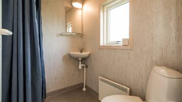A bathroom with a white sink, a toilet, and a window.