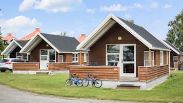 A row of wooden cabins with pitched roofs, each featuring a front door and windows.