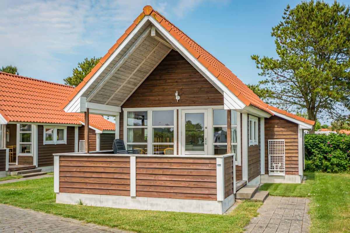 A wooden cabin with a sloped roof and large windows.