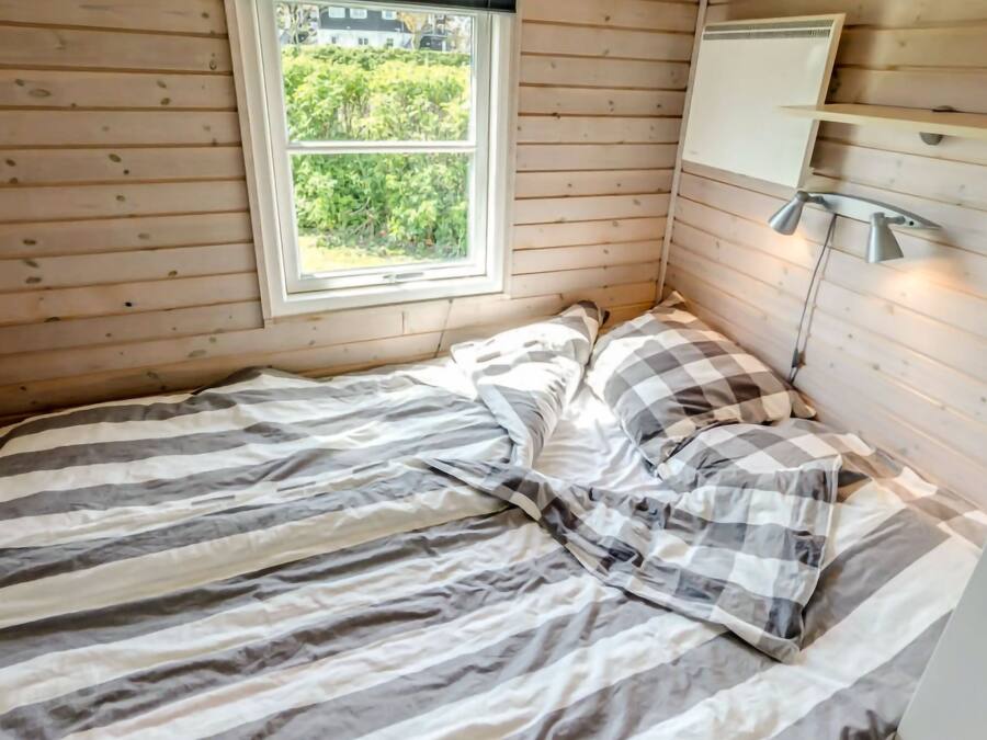 Un dormitorio pequeño con una cama individual, una ventana y una lámpara de noche.