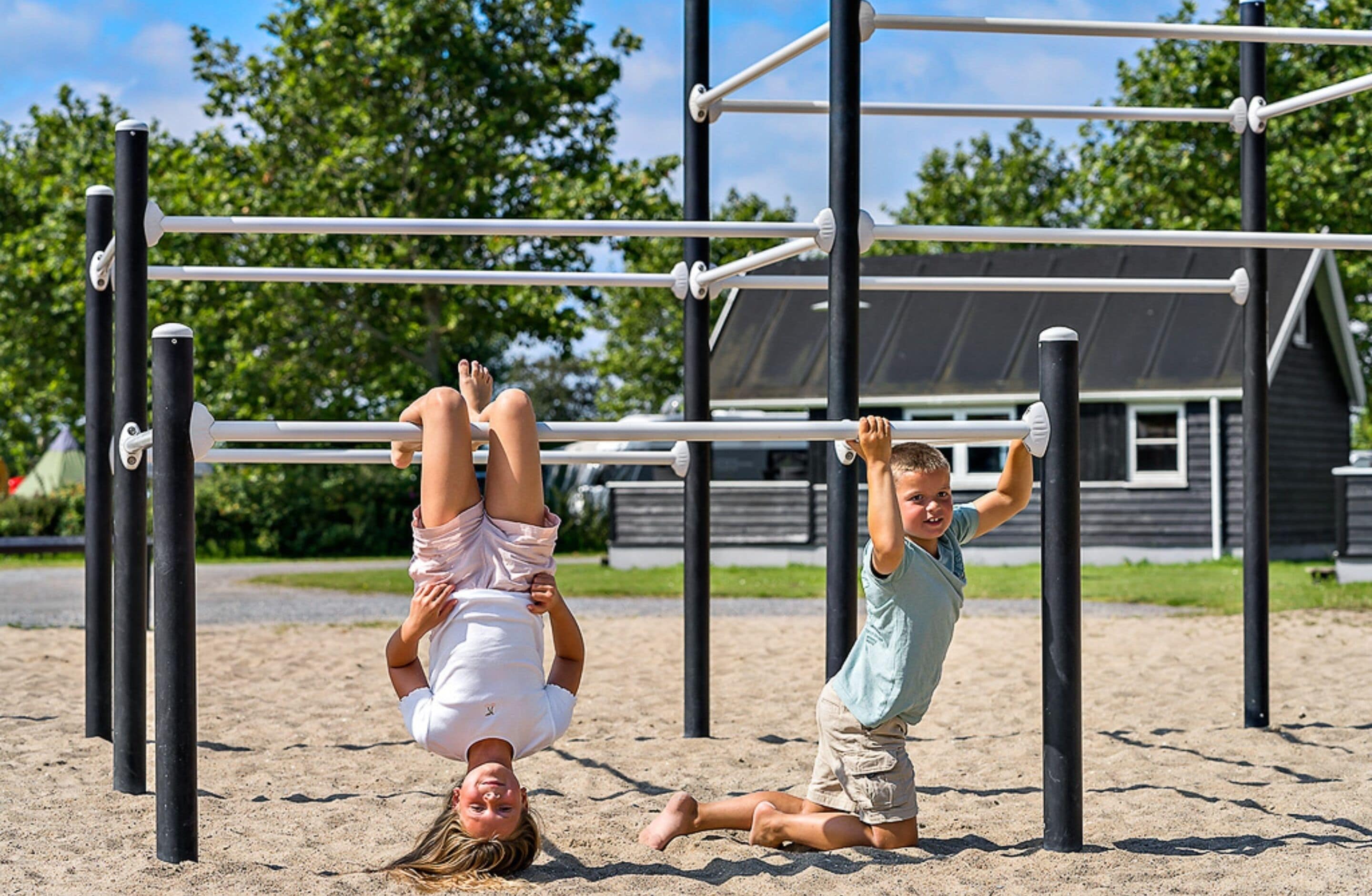 A playground with monkey bars and a sand area.