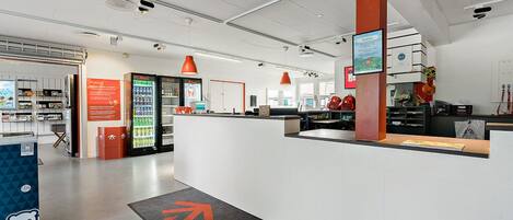 A modern reception area with a counter, a beverage fridge, and directional arrows on the floor.