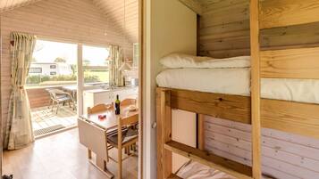 A cozy cabin with a bunk bed, a dining area with a table and chairs, and a view of the outdoors.