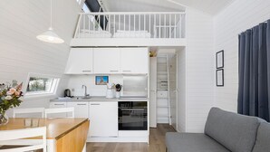 Un apartamento moderno y compacto con kitchenette, comedor y dormitorio en loft.