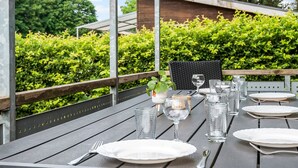 A dining table set outdoors with plates, glasses, and cutlery.