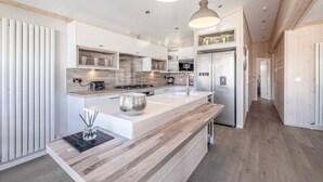 A modern kitchen with a central island, built-in appliances, and pendant lighting.