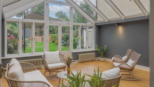 A conservatory with wicker furniture, large windows, and a view of a garden. - 4 Bed Family Home In Windsor - By Tempstay (Old Windsor)